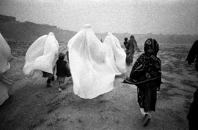 Provincia di Takhar, nei pressi del villaggio di Khoja Bahauddin, Afghanistan. 2001 Alcune donne e bambini si dirigono verso il campo profughi di Dashti Kola durante una tempest di sabbia.